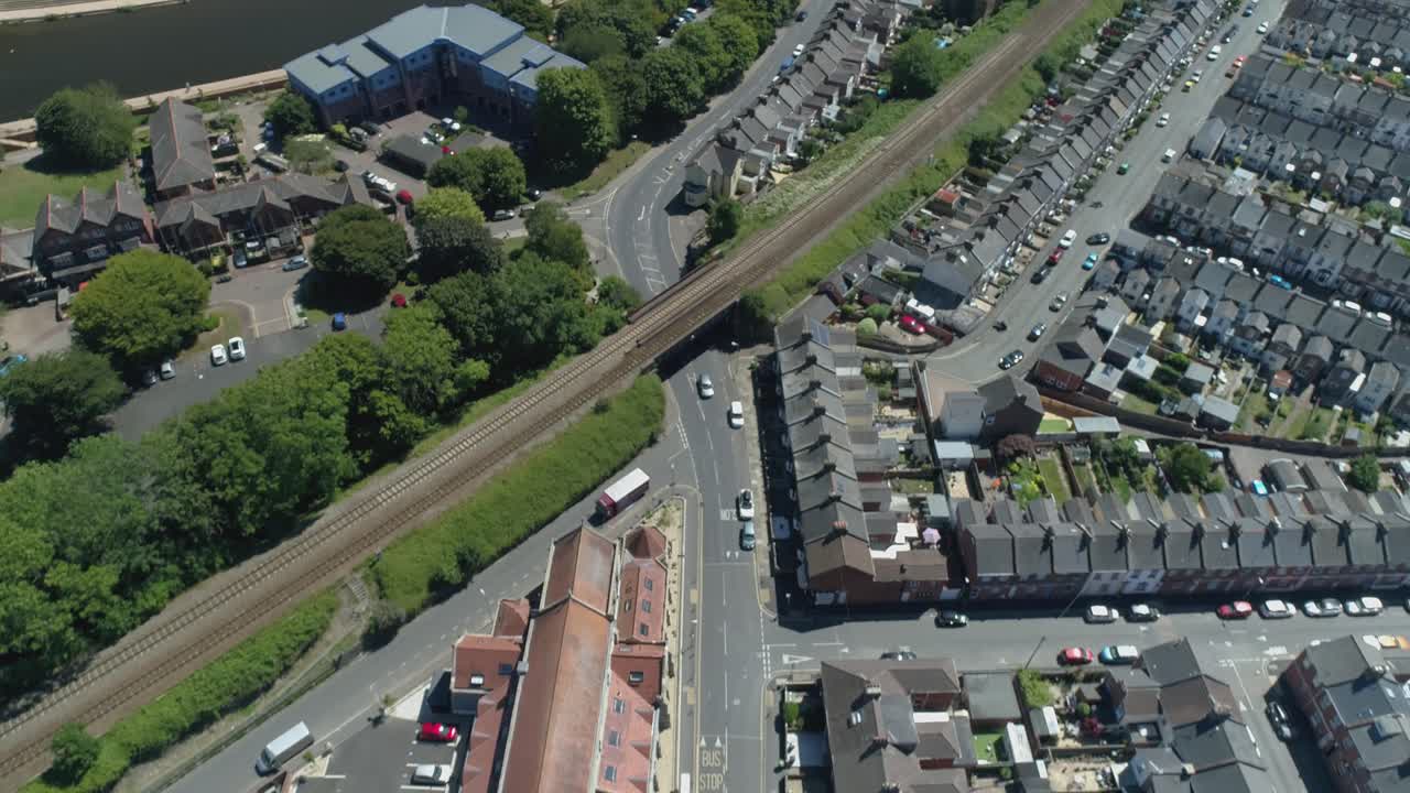 antena de la línea de tren y calles residenciales en la inglaterra urbana en un día soleado, río e instalaciones comunitarias también visibles
