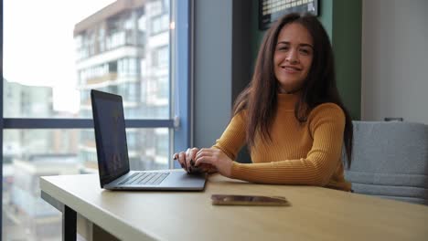 a woman works diligently at her table focused on her tasks. in this video, a focused woman works diligently at her table, using a laptop and phone, showcasing her productivity and modern work life