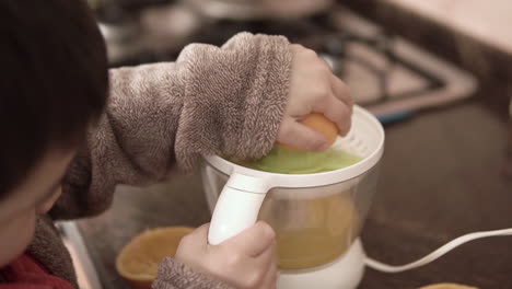 asian kid making natural fresh squeezed orange juice by himself