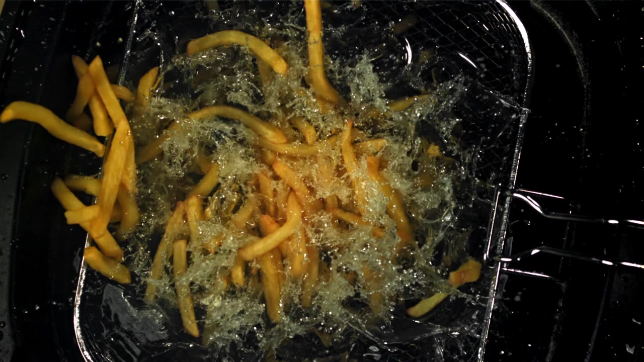 Gylne pommes frites som slippes ned og friteres i varm olje