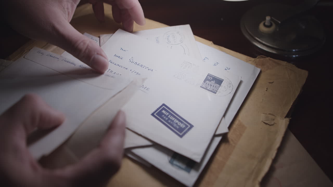 руки мужчины в кадре ищут письмо в стопке писем