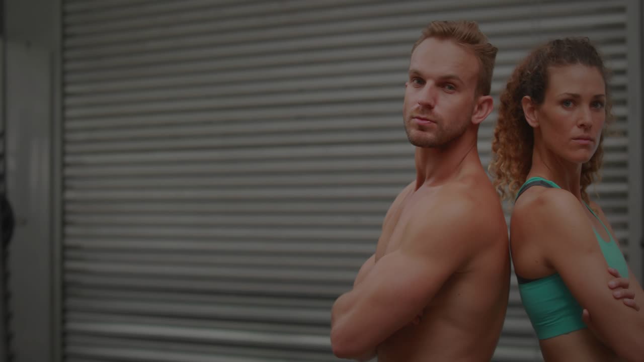 Code overlay fading in, causing fitness duo by rollup door smiling and giving thumbsup for promo