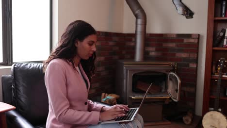 una mujer joven escribe en su computadora portátil frente a un horno antiguo