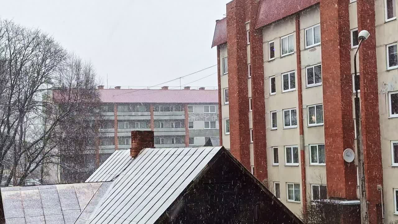 Residential buildings and roofs covered with fresh snow in snowfall on a gloomy day