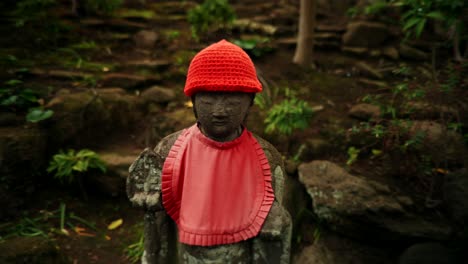 stone statue with red hat and bib in a japanese garden