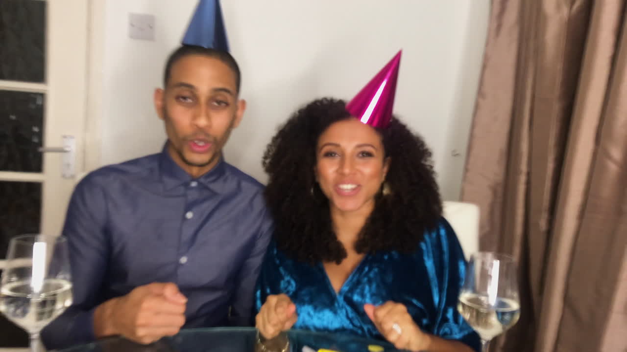 pareja de adultos jóvenes en videollamada contando hasta la medianoche y celebrando el cambio de año juntos