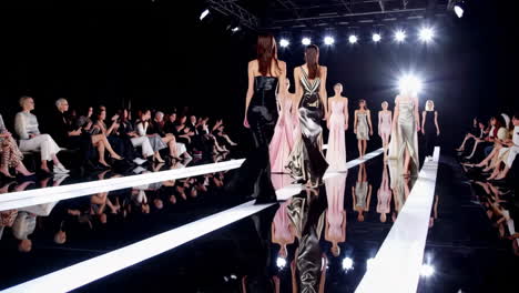 models showcasing elegant dresses on a glossy runway at a fashion show