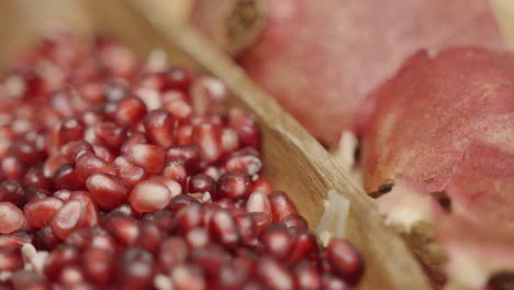 close up panning of pomegranate seeds inside of a plate juicing and using fresh ingredients and fresh whole pomegranates