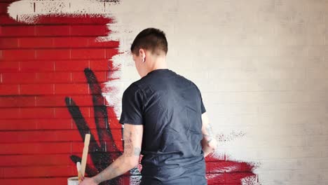 person whitewashing a red painted brick wall