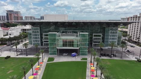 modern dr. phillips center building in orlando city with palm trees and parking cars. cloudy day in florida, usa. aerial approaching shot. performing arts center in downtown.