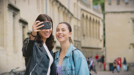 Feliz-Pareja-De-Mujeres-Del-Mismo-Sexo-Haciendo-Turismo-Mientras-Posan-Para-Selfie-Y-Caminan-Juntas-Por-Oxford,-Reino-Unido