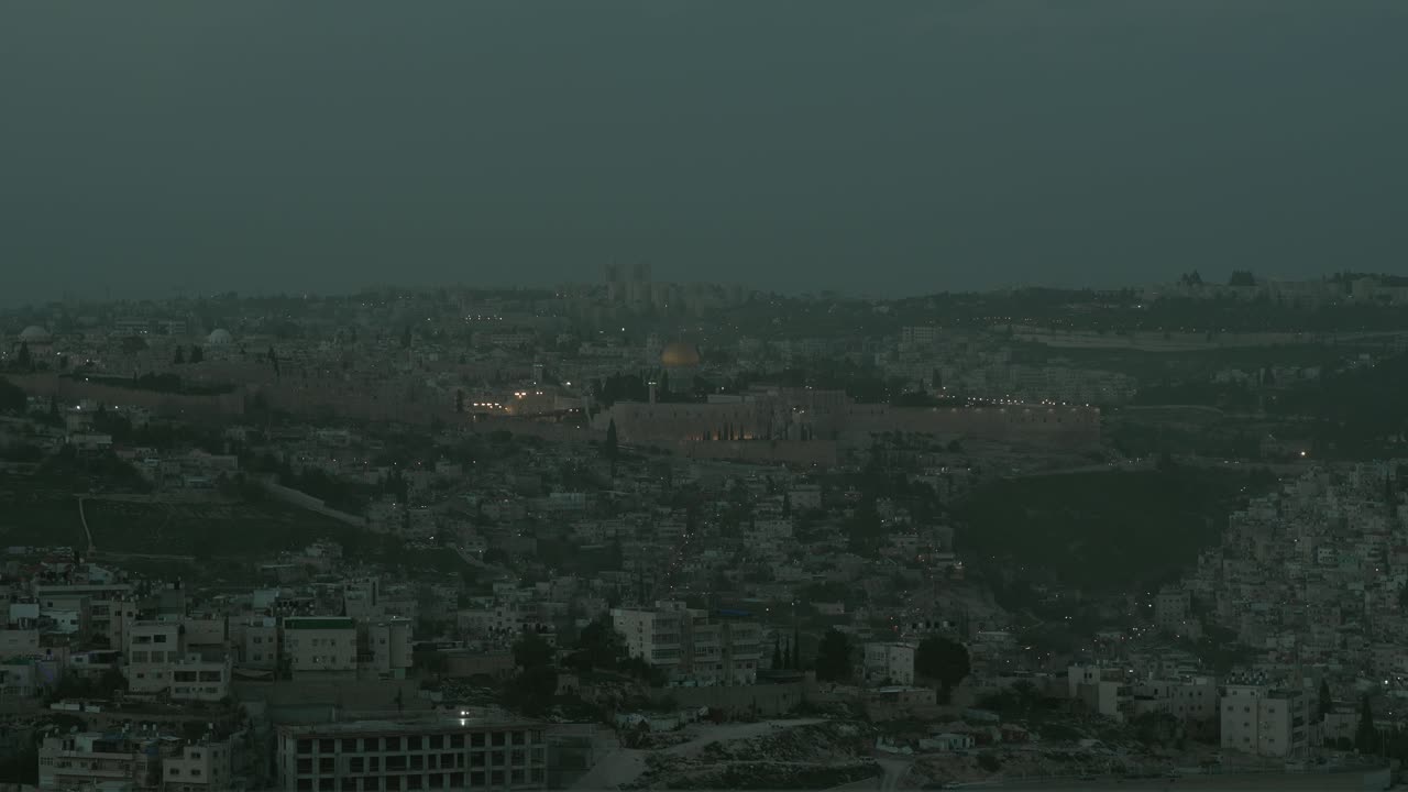 Bellissima transizione time-lapse dal giorno alla notte sulle mura della Città Vecchia, sulla Cupola della Roccia e sul Monte del Tempio a Gerusalemme. Lo storico e sacro paesaggio urbano si illumina mentre il crepuscolo si trasforma in notte.