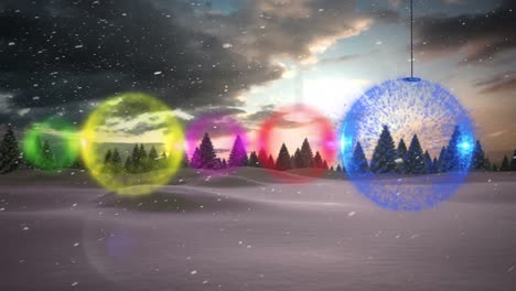 Colorful-bauble-decorations-hanging-against-snow-falling-over-winter-landscape