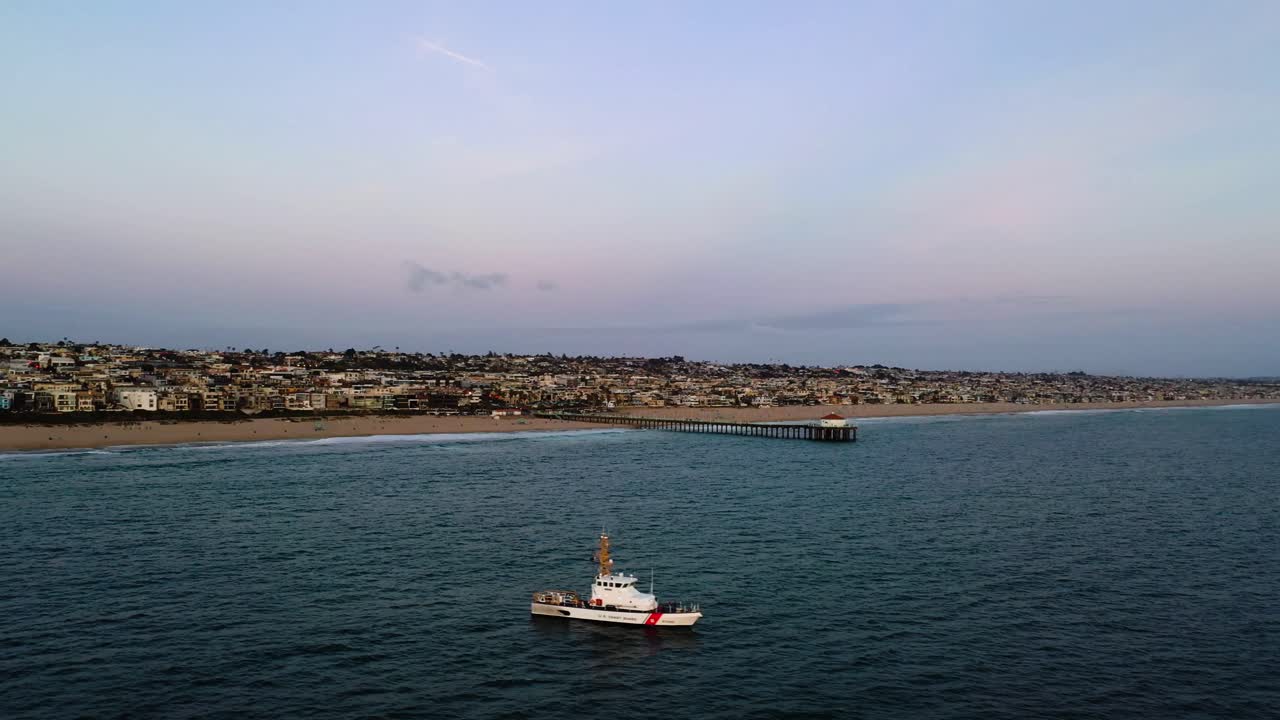 barco de guardacostas de vela en aguas tranquilas del océano pacífico cerca del muelle de la playa de manhattan en california, ee.uu.