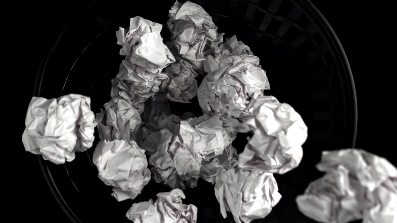 Palline di carta accartocciate che cadono in un cestino dei rifiuti su sfondo nero