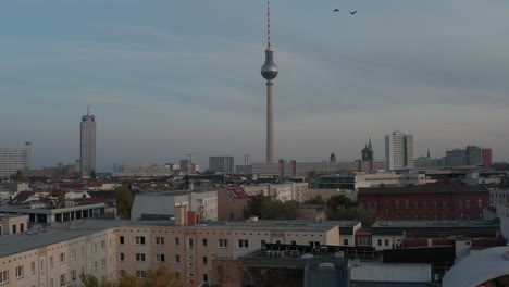 Adelante-Volando-Por-Encima-De-Varios-Edificios-Cerca-Del-Centro-De-La-Ciudad.-Hito-Famoso-Y-Popular,-Torre-De-Televisión-De-368-Metros-De-Altura,-Fernsehturm.-Berlín,-Alemania.