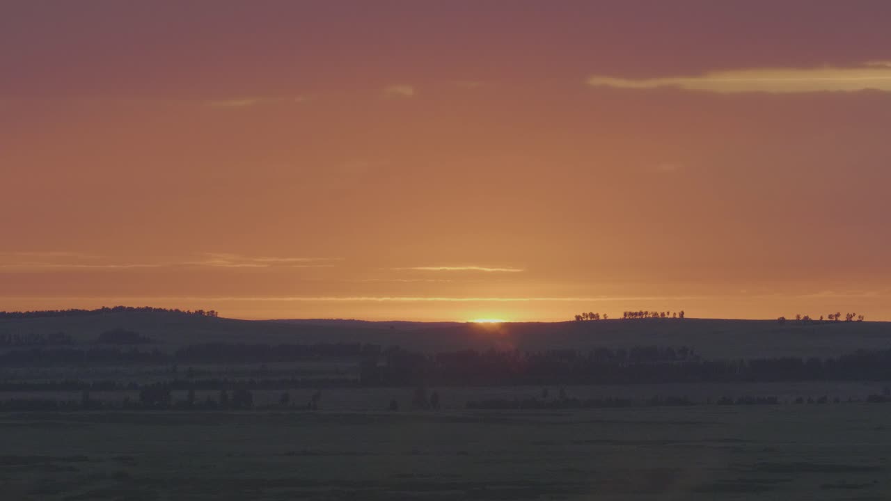 amanecer o atardecer sobre un campo y colinas