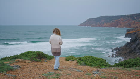 relaxed tourist walking ocean coast at windy cold day. woman stepping shore