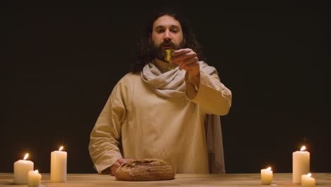 fotografía de estudio de un hombre vestido con túnicas, cabello largo y barba que representa la figura de jesucristo predicando 1