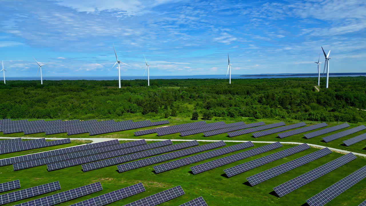 Drone shot of a wind park and solar system in estonia with a lot of green forests in slowmotion