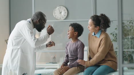 Doctor-Examining-Throat-of-African-American-Boy-with-Flashlight