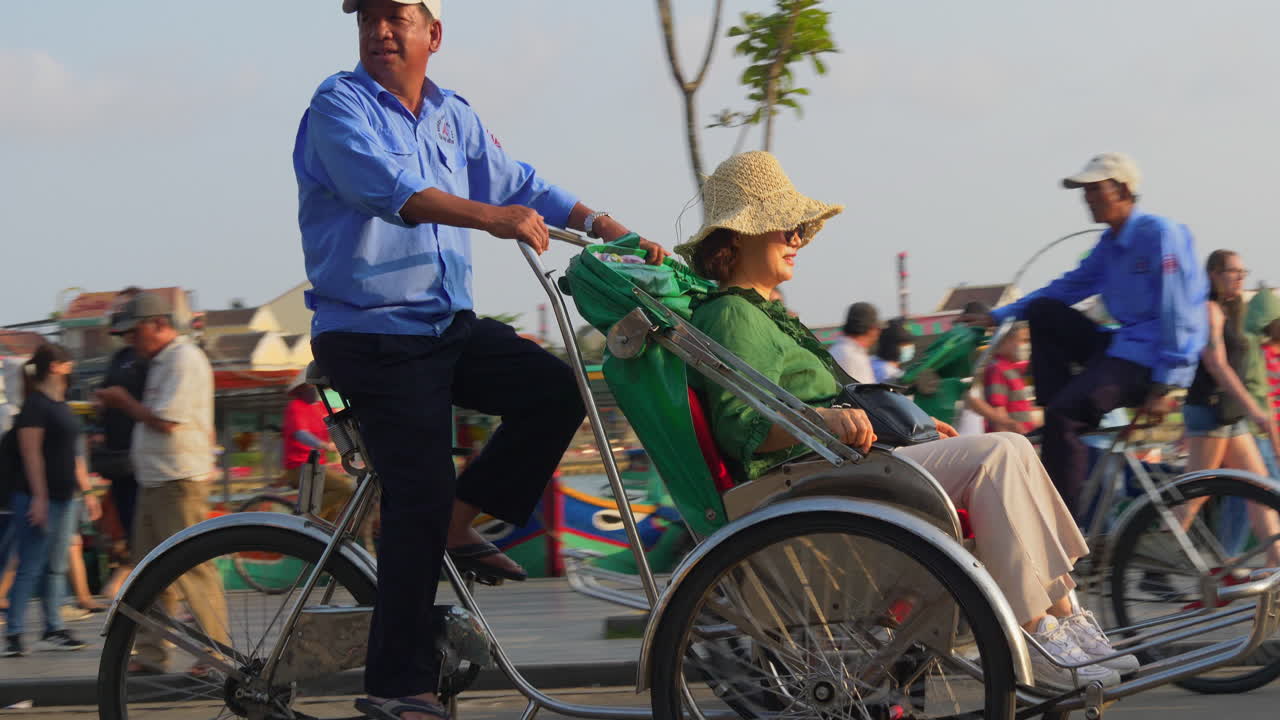 A tracking footage of a tourist on a cyclo rental transpo driving around the city of Hoi An in Vietnam. They are moving towards the sunset.