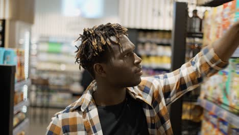 un guapo hombre afroamericano elige copos de maíz en la tienda de comestibles