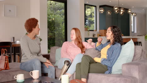 chatting and relaxing on couch, diverse female friends enjoying coffee together indoors