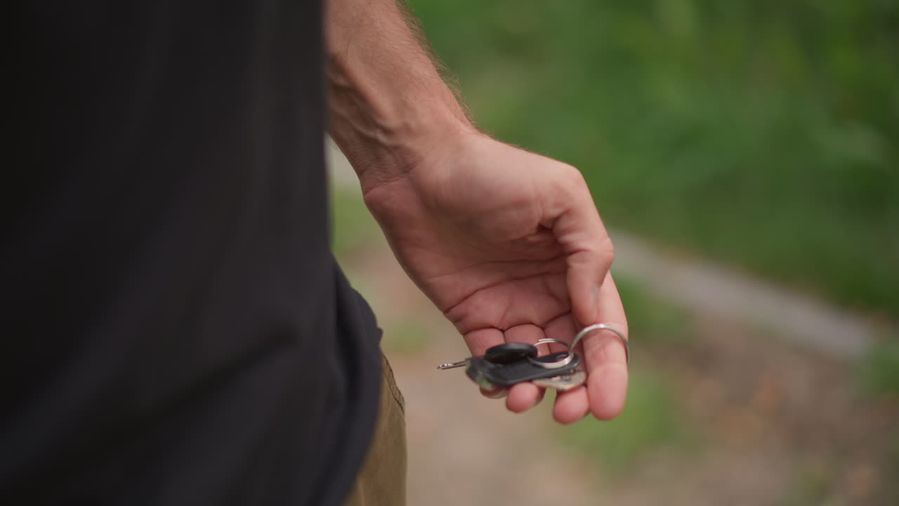 Relaxed Individual With Keys During Outdoor Break, Person Standing With Keys Beside During Casual Outdoor Pause, Individual Relaxedly Holding Keys As They Pause Briefly On Walking Trail