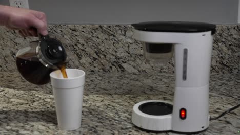un hombre vierte café caliente fresco que hizo en una taza de poliestireno