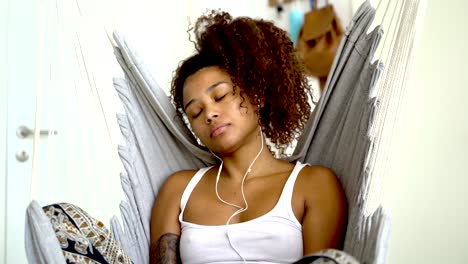 Young-black-woman-with-earphones-taking-using-mobile-phone-at-home