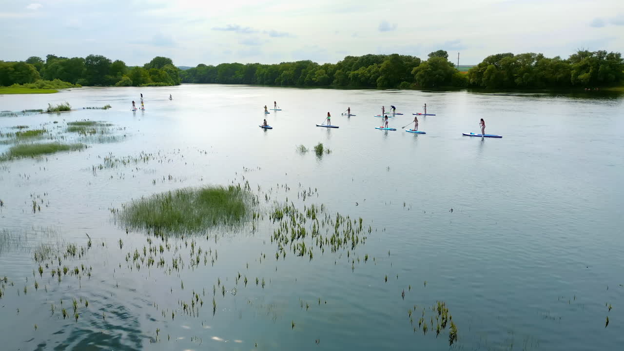 Luftfoto af flere personer, der står op og paddleboarder på Dniester-floden i Moldova. Frodig skov på begge sider af floden.
