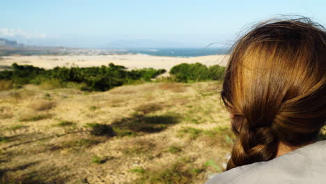 a woman pulls down a hoodie looking at scenic landscape across the beach of pan rang in vietnam on a windy summers day