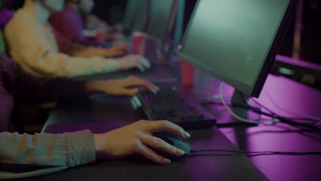 gros plan sur la main d'une joueuse sur une souris d'ordinateur jouant à des jeux vidéo virtuels tout en étant assise avec son équipe dans un club de jeu