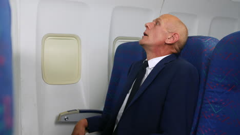 a stressed mature business man panicking with anxiety and a fear of flying on an airliner airplane