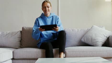 mujer joven usando una tableta en un sofá