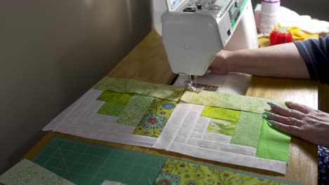 senior woman using a sewing machine to stitch together quilt blocks