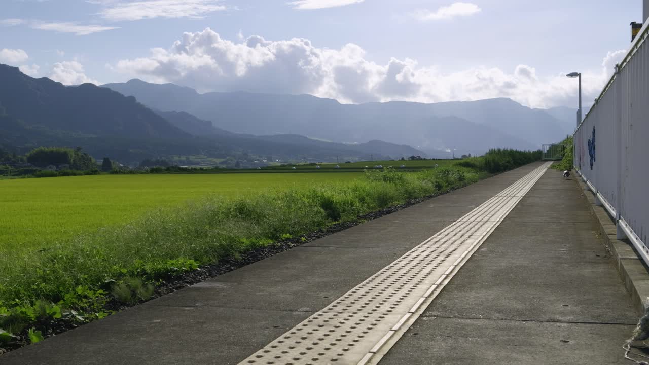 Rural train station in Aso, Kyushu with rice fields in distance