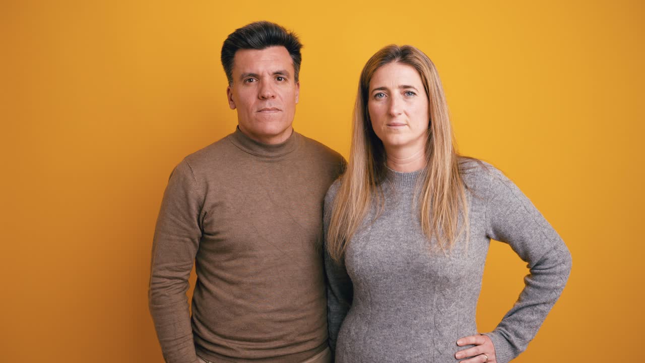 Hombre y mujer serios de pie juntos sobre fondo amarillo