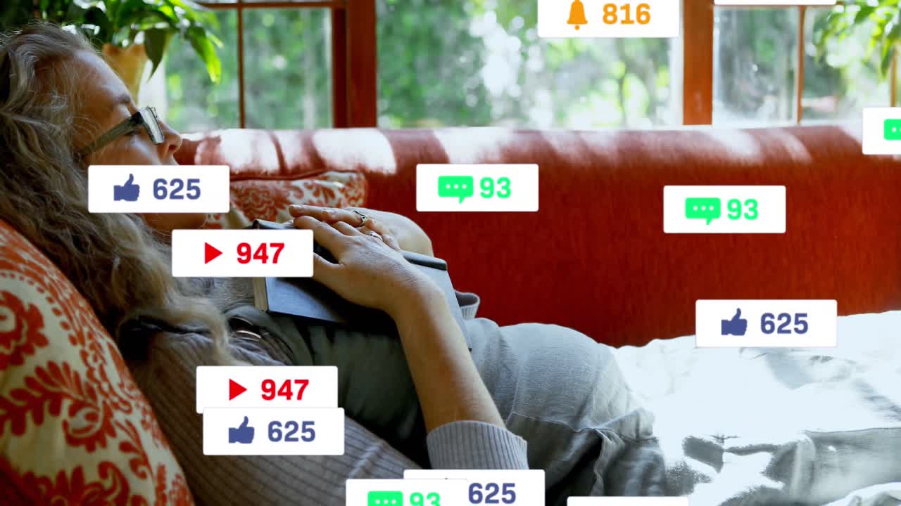 animación de iconos de las redes sociales sobre una mujer anciana caucásica sosteniendo un libro durmiendo en el sofá
