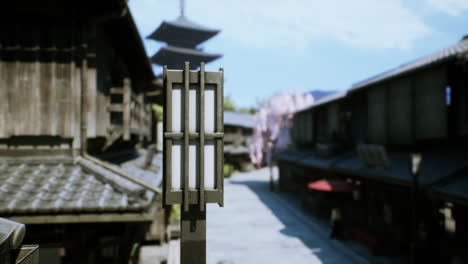 A traditional Japanese street with a lantern, buildings, and a temple in the background