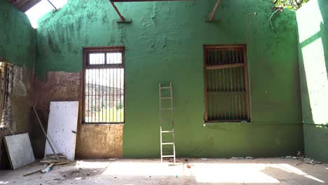 abandoned building with boarded up windows with ladder and trash on floor