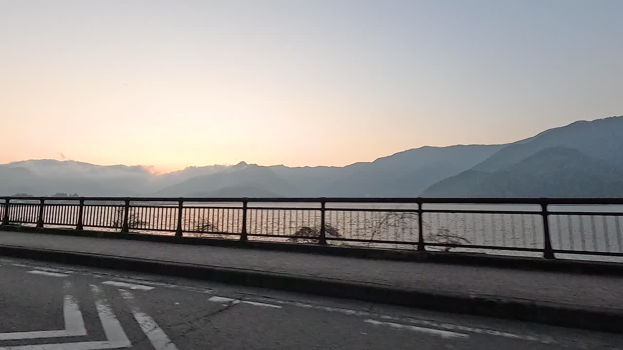 A serene drive along Lake Kawaguchi at sunrise, capturing tranquil mountain views and soft morning light