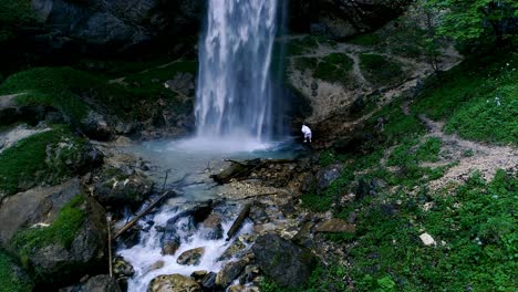 man with beard is doing waterfall-meditation under big waterfall