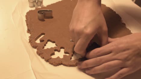 cutting out different christmas themed cookies from caramel rolled dough