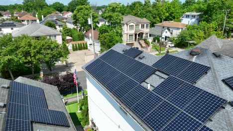 Aerial-flight-over-american-building-with-modern-solar-panel-units-on-roof-and-american-flag-in-garden