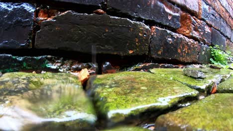 agua de lluvia goteando, vertiéndose sobre adoquines en un antiguo callejón de adoquines en el distrito de stoke on trent, viviendas con terraza y áreas pobres de la comunidad local