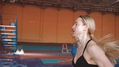 side view of two multiethnic female athletes running together on an indoor track 1