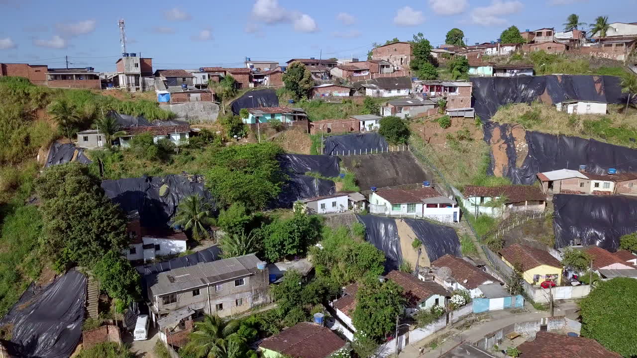 Elevated daytime view of the Macaxeira community on a hill in Recife Pernambuco showing basic homes cars and widespread tarpaulins that underscore conditions of poverty potential danger and inequality