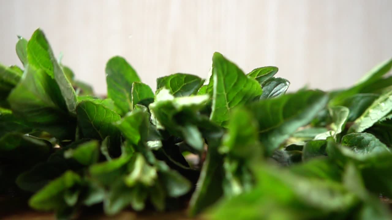 Caduta di foglie di menta su un tagliere. Al rallentatore.